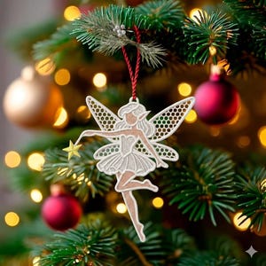 Può includere: Un ornamento natalizio a forma di fata bianca e beige con una bacchetta a stella, appeso a un albero di Natale. La fata ha ali dettagliate e un tutù. L'ornamento è sospeso da una corda rossa, con decorazioni per l'albero di Natale sullo sfondo.