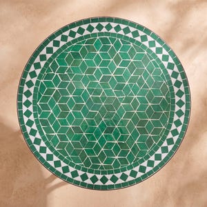 Peut inclure: Un plateau de table rond orné d'une mosaïque de carreaux verts en forme de losange disposés en un motif géométrique cubique. Le centre est entouré d'une bordure de carreaux carrés blancs et verts alternés, le tout dans un cadre en métal sombre.