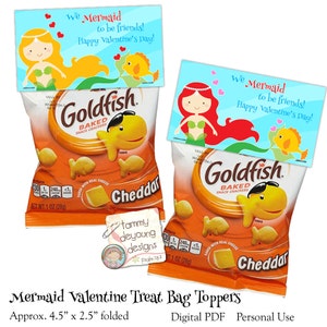 May include: Two printable Valentine's Day treat bag toppers featuring a mermaid with a goldfish. The toppers are designed to fit a standard-sized bag of Goldfish crackers. The text on the toppers reads "We Mermaid to be friends! Happy Valentine's Day!"