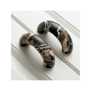 Peut inclure: Une tasse en céramique blanche avec une anse noire et le texte "But First, Coffee" en gras noir. La tasse est posée sur un fond neutre, soulignant son design simple.