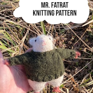 Può includere: Un giocattolo a forma di ratto lavorato a maglia con un maglione verde. Il ratto è bianco con accenti rosa sul naso e sui piedi. Il testo "MR. FATRAT KNITTING PATTERN" è in una casella di testo bianca a forma di nuvola.