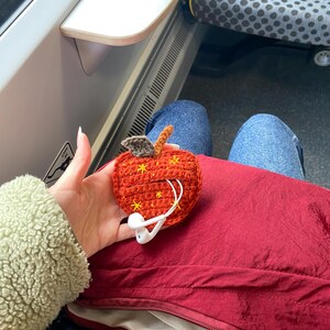 Crochet pouch for wired earphones. Small red apple with yellow embroidered stars, brown stem and dark green leaf on top