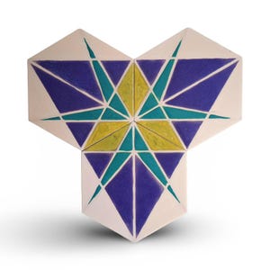 Puede incluir: Tres baldosas hexagonales dispuestas en forma de estrella. Las baldosas tienen un fondo crema con diseños geométricos en azul, turquesa y amarillo. El diseño simétrico es visualmente atractivo.