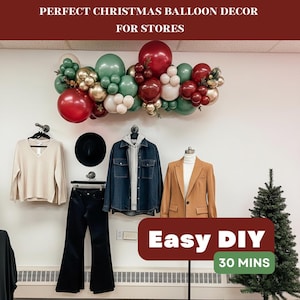 May include: A Christmas balloon garland in red, green, gold, and white decorates a wall above a clothing display. The display includes a beige sweater, black pants, a denim jacket, a black hat, and a tan blazer. The text "Perfect Christmas Balloon Decor For Stores" and "Easy DIY 30 Mins" are visible.