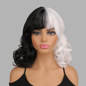 May include: A two-toned wig with a black and white split design. The wig features a side part with black hair on the left and white on the right. The hair is styled with soft waves and a fringe.