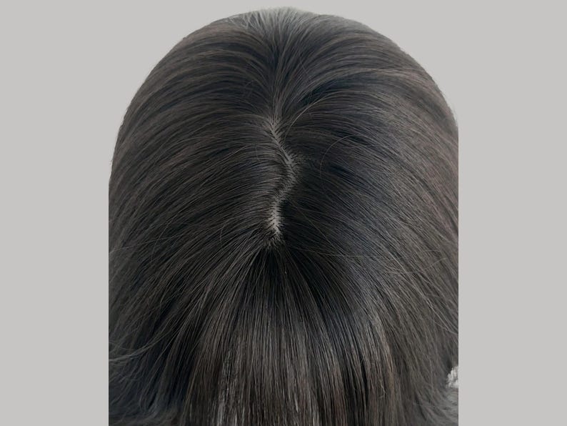 May include: Close-up of a dark brown wig with a visible part. The hair is styled with a natural look, and the strands appear smooth and straight. The wig is likely designed for fashion or cosmetic purposes.