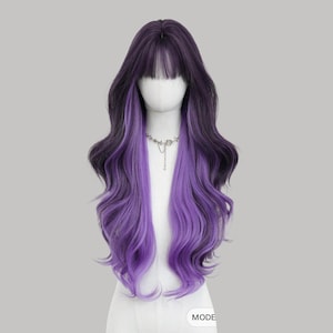 May include: A long, wavy wig with a dark purple base and vibrant purple highlights. The wig features a blunt fringe and is styled on a mannequin head. A silver necklace is visible.