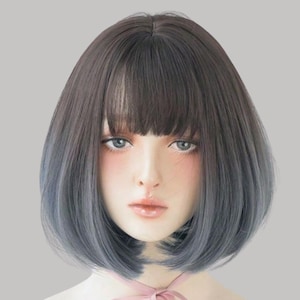 Może przedstawiać: Peruka w stylu bob z efektem ombre od ciemnobrązowego do niebieskiego. Peruka ma tępe cięcie z grzywką, a włosy są ułożone tak, aby oprawiały twarz. Peruka została zaprojektowana tak, aby wyglądać naturalnie.
