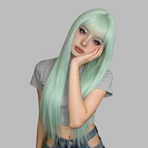 May include: A long, straight, mint green wig with bangs, featuring a smooth texture and a center part. The hair falls past the shoulders in a sleek, layered style, showcasing a vibrant, solid pastel green color throughout the entire length.