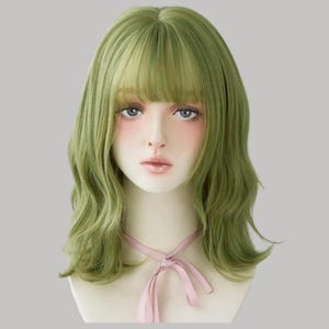 Puede incluir: Cabeza de maniquí con una peluca verde con capas onduladas y flequillo. La peluca tiene un estilo natural y es de un tono verde vibrante. Una cinta rosa está atada alrededor del cuello del maniquí.