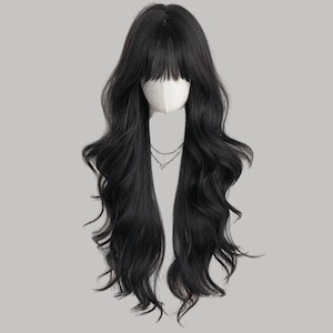 May include: A long, wavy black wig with a blunt fringe. The wig is styled on a mannequin head, and a delicate silver necklace is visible. The hair cascades down in loose waves, creating a natural and voluminous look.