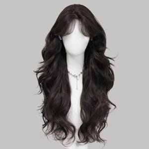 Puede incluir: Peluca marrón oscuro con cabello largo y ondulado y un flequillo en capas. La peluca está peinada sobre una cabeza de maniquí y se ve un collar plateado. El cabello tiene un aspecto natural y cae sobre los hombros.