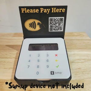 May include: A white and black payment terminal with a numeric keypad and a display screen. The terminal has a black stand with the text "Please Pay Here" and a QR code. The image also includes the text "Sumup device not included".