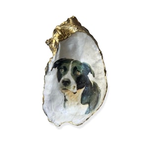 May include: A black and white dog portrait painted on a white oyster shell with gold accents.