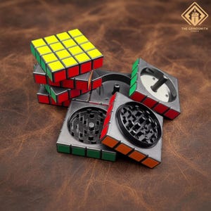 May include: A multi-piece grinder with a Rubik's Cube design. The grinder is silver with red, yellow, green, and orange accents. The top of the grinder has a black, patterned grinding surface. The logo "THE GRINDSMITH STUDIO" is in the top right corner.