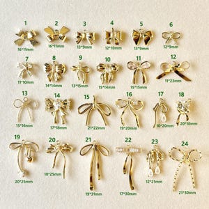 以下が含まれることがあります： さまざまなデザインとサイズの金色のリボンチャームのコレクション。各チャームには番号とミリメートル単位の寸法が記載されています。これらの装飾チャームは、ジュエリー作りやその他のクラフトプロジェクトに適しています。
