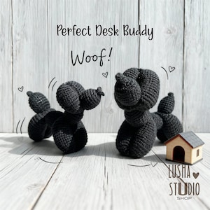 Puede incluir: Dos esculturas de perro de ganchillo negro, que se asemejan a animales de globo, se exhiben sobre una superficie de madera clara. El texto "Perfect Desk Buddy" y "Woof!" están encima de los perros. También hay una pequeña casa de madera.