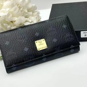 May include: Black leather wallet with a repeating pattern and a gold-coloured logo. The wallet is folded and has a textured surface. A black box with the text "004# 黑色" is in the background.