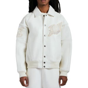 Puede incluir: Chaqueta universitaria color crema con cierre de botones, cuello y pu&ntilde;os y dobladillo acanalados. La chaqueta tiene un parche en el pecho y la manga izquierda con el texto "USA". La chaqueta est&aacute; hecha de un material liso con detalles de malla.