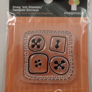 May include: A clear plastic sheet with four different button-shaped stamps. The stamps are arranged in a grid pattern. The stamps are designed to be used with an ink pad. The text on the packaging reads "Snag 'em Stamps/Tampon Encreur" and "Another sweet stamp from Imaginisce."