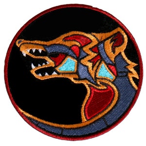 May include: Embroidered patch with a stylized wolf head design. The wolf's head is red, blue, gold, and turquoise on a black background. The patch is surrounded by a red border.