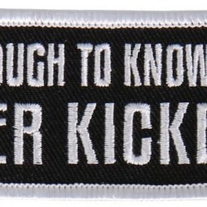 May include: Black and white embroidered patch with white text that reads "Old Enough To Know Better Never Kicked In".