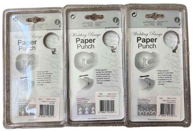 K&ouml;nnte beinhalten: Drei transparente Plastikverpackungen mit wei&szlig;em Hintergrund, jede mit einer silbernen Papierstanze mit der Aufschrift "Wedding Range Paper Punch". Die Verpackungen sind mit der Produktnummer 791, 790 und 792 gekennzeichnet.