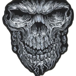 May include: A black and white embroidered skull patch with a detailed design. The skull has a large, toothy grin and a dripping effect around the mouth.