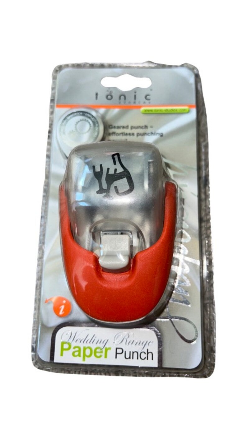 K&ouml;nnte beinhalten: Ein roter und silberner Papierstanzer mit einem Design aus Weinflasche und Gabel. Der Stanzer ist in einer durchsichtigen Plastikverpackung verpackt, auf der vorne der Text "Wedding Range Paper Punch" steht.
