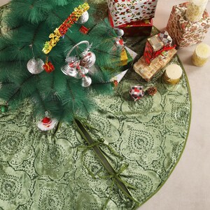 Puede incluir: Una falda de &aacute;rbol de Navidad verde con un estampado floral rodea un &aacute;rbol de Navidad artificial decorado. Los regalos envueltos en papel festivo y las velas est&aacute;n dispuestos alrededor del &aacute;rbol, creando una escena navide&ntilde;a.