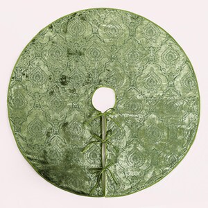 Puede incluir: Una falda redonda de &aacute;rbol de Navidad de terciopelo verde con un patr&oacute;n de damasco ornamentado. La falda tiene una abertura circular para el tronco del &aacute;rbol y est&aacute; bordeada con un borde verde a juego. Se adjuntan cintas verdes para sujetarla.