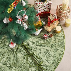 Puede incluir: Un &aacute;rbol de Navidad decorado con adornos y regalos envueltos. El &aacute;rbol se encuentra sobre una falda de &aacute;rbol verde con un estampado floral. Los regalos est&aacute;n envueltos en papel festivo. Tambi&eacute;n hay velas y una pi&ntilde;a.
