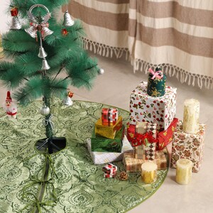 Puede incluir: Un &aacute;rbol de Navidad decorado con adornos y una falda de &aacute;rbol verde. Regalos envueltos en varios tama&ntilde;os y patrones est&aacute;n dispuestos alrededor del &aacute;rbol. La falda del &aacute;rbol tiene un dise&ntilde;o de cachemira verde.