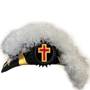 Op de afbeelding: Zwarte en gouden hoed met een rood kruis embleem. De hoed heeft een grote witte verenpluim en gouden afwerking. Het embleem is een rood kruis op een zwarte achtergrond met een gouden rand.