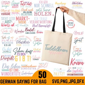 Peut inclure: Un sac fourre-tout crème avec des anses noires est tenu par une personne. Le sac affiche le texte "Tüddelkram" en script bleu clair avec des accents floraux roses et verts. Diverses phrases allemandes entourent le sac.