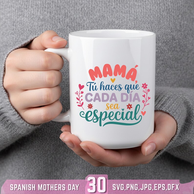 May include: White ceramic mug with the Spanish text "MAMA T&uacute; haces que CADA D&Iacute;A sea especial" in red, teal, and purple. The mug has a white handle and is decorated with floral and heart accents. A perfect gift for Mother's Day.