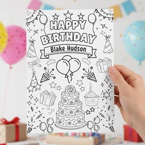 Puede incluir: Una p&aacute;gina para colorear en blanco y negro con el tema de cumplea&ntilde;os con el texto "HAPPY BIRTHDAY Blake Hudson". El dise&ntilde;o incluye globos, estrellas, gorros de fiesta, regalos, una tarta de tres pisos y una magdalena. La p&aacute;gina est&aacute; sujeta por una mano.
