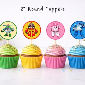 Puede incluir: Cuatro cupcakes con glaseado colorido y envoltorios de papel a juego. Cada cupcake tiene un adorno redondo de 5 cm con un personaje de dibujos animados. Los adornos están sobre palitos de madera. El texto "2" Round Toppers" está en la parte superior.