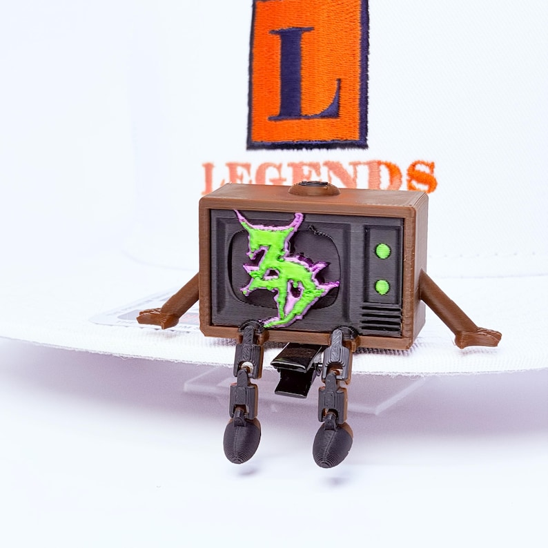 Zeds Dead articulated TV buddy sitting on a white brim with legs dangling