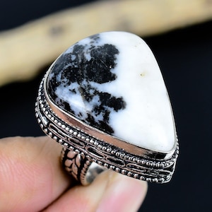 Può includere: Anello d'argento con una grande pietra triangolare con un sorprendente motivo bianco e nero. La pietra è incastonata in una fascia d'argento dettagliata e ornata. Il design dell'anello è accattivante e unico, adatto a qualsiasi collezione di gioielli.