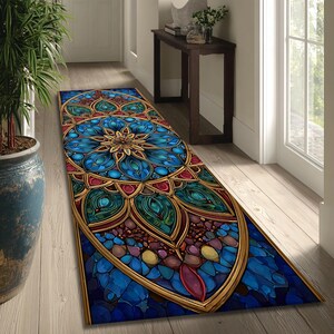 Op de afbeelding: Een decoratieve loper met een glas-in-lood ontwerp. Het tapijt heeft een centraal bloemmotief in tinten blauw, teal en goud, omlijst door een gouden rand. Het ontwerp bevat rode en paarse accenten, waardoor een levendige en artistieke uitstraling ontstaat.