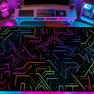 May include: A rectangular area rug with a black background and a neon circuit board design. The rug features lines in shades of pink, purple, blue, green, and orange. The rug is placed in a room with gaming equipment and neon lighting.