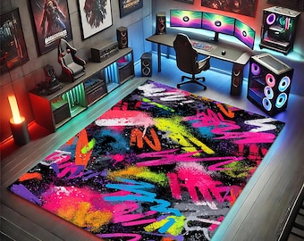 May include: A rectangular area rug featuring a black background with a vibrant, multi-colored graffiti-style pattern. The design includes chaotic brushstrokes and splatters in neon pink, electric blue, bright yellow, orange, and purple.
