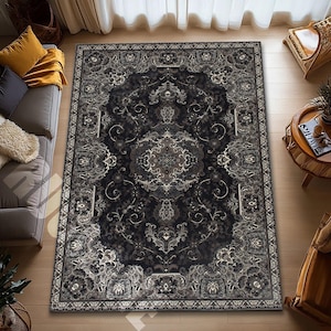 May include: A large, rectangular area rug with an ornate, traditional design. The rug features a dark gray and black central field with a detailed floral and geometric pattern. The border is a lighter gray with a repeating design.