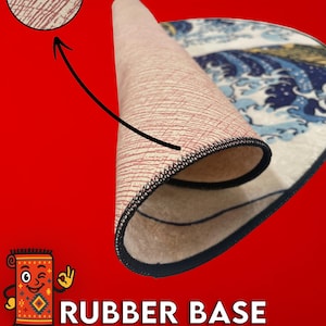 May include: A rolled-up rug with a blue and white wave design, revealing a beige rubber base with a red pattern. The rug has a black stitched edge. Text on the image reads "RUBBER BASE (NONSLIP)".