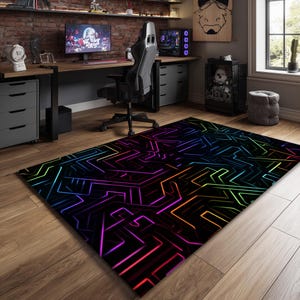 May include: A rectangular area rug with a black background and a neon geometric design in shades of purple, pink, orange, green, and blue. The rug is placed on a wooden floor in a room with a desk and computer.