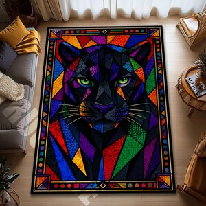 May include: A rectangular area rug featuring a geometric design of a black panther's face. The panther's eyes are green, and the design incorporates various colors, including red, orange, yellow, green, blue, and purple. The rug has a black border.