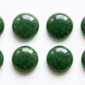Pode incluir: Oito cabochões circulares, lisos e de cor verde-escura, dispostos em duas filas de quatro. Cada peça apresenta uma superfície polida e refletora com um subtil mosqueado interno e um topo abobadado, mantendo uma aparência uniforme e consistente.