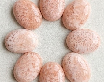 May include: Seven oval-shaped cabochons arranged in a circular pattern. Each stone features a smooth, polished surface with a soft peach and cream colour palette, displaying intricate, radiating, and speckled natural patterns throughout the material.