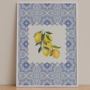 Peut inclure: Une impression encadrée avec une illustration à l'aquarelle de citrons et de feuilles vertes. Les citrons sont placés sur un fond blanc, encadrés par une bordure à motifs bleus et blancs, rappelant des carreaux décoratifs.